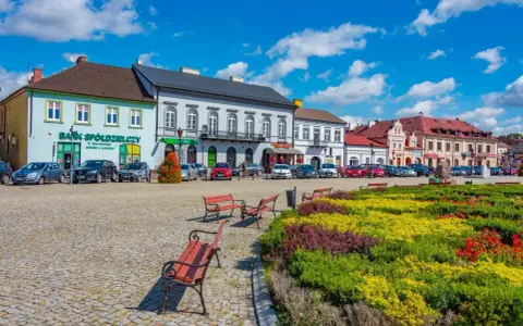 Kolorowy rynek z kwitnącymi rabatami i ławkami, idealne miejsce na wyjazd na weekend.