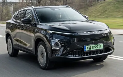 Czarny OMODA elektryk w ruchu drogowym. Nowoczesny design z charakterystycznym pasem świateł LED i logo marki.