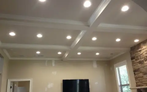 Elegancka wnęka na led w suficie z kasetonami i ozdobnymi listwami, tworząca nowoczesną aranżację wnętrza.