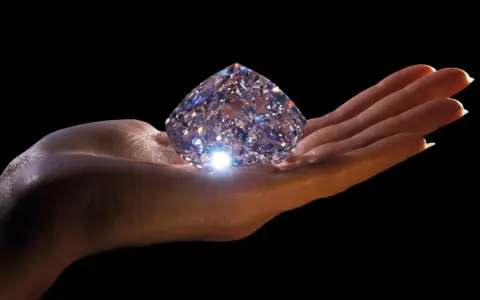 Mano che regge un enorme diamante scintillante, simbolo di eternità e amore. Il diamante significato è immenso.