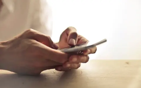 Dłonie trzymające telefon, jakby zastanawiając się, czy na odwyku można mieć telefon.