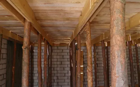 Szalowanie stropu z drewnianymi stemplami, tworzącymi rusztowanie pod przyszły strop.