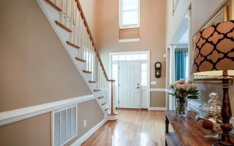 Pasillos con encanto: escalera de madera, puerta blanca y un jarrón con rosas.