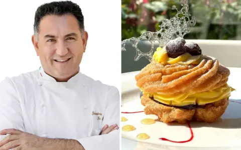 Chef sorridente accanto a una deliziosa zeppola di San Giuseppe, guarnita con crema pasticcera, amarene e decorazione di zucchero.
