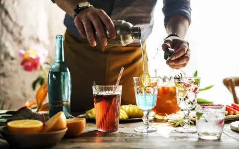 Barman przelewa płyn z shakera do drinka, tworząc kolorowe koktajle. Mieszanie alkoholi to sztuka.