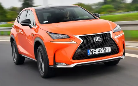 Pomarańczowy Lexus NX 300h w ruchu, z widocznym kierowcą.