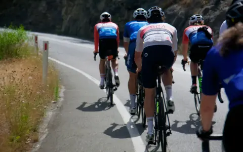 Cyclists in racing gear tackle a steep road, their shadows stretching long on the asphalt. This is the essence of category climbs cycling.