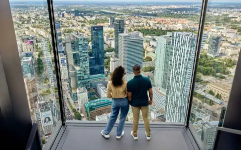 Para zwiedzająca Varso Tower taras widokowy, podziwia panoramę Warszawy.
