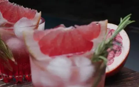 Erfrischende sommer drinks mit tonic water, Eiswürfeln und Grapefruit-Garnitur. Ein Hauch Rosmarin rundet das Bild ab.