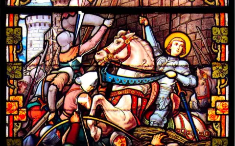 Vitrail de Jeanne d'Arc, la Pucelle d'Orléans, en armure sur son cheval blanc, brandissant son épée au milieu d'une bataille.