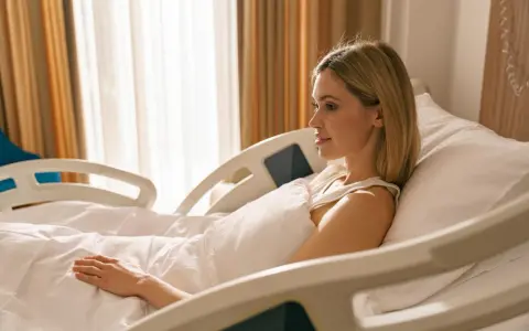 Kobieta w szpitalnym łóżku, które może być wyposażone w różne rodzaje materacy przeciwodleżynowych, aby zapewnić komfort i zapobiegać odleżynom.