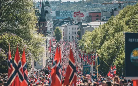 Tłum ludzi na ulicy w Oslo, z norweskimi flagami. Czy Norwegia jest w NATO? Tak, jest członkiem od 1949 roku.