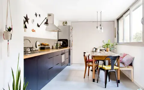 Cuisine sans placard haut, avec des meubles bas sombres, un plan de travail en bois et une table à manger.