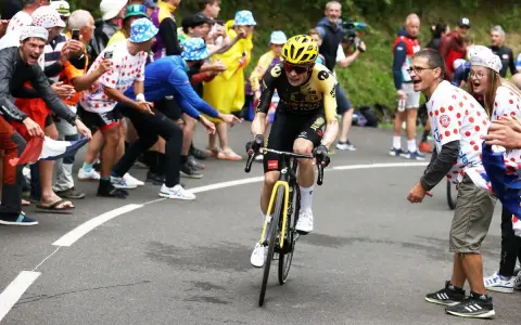 Jonas Vingegaard, with his impressive VO2 max, powers through a crowd of cheering fans in a cycling race.