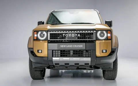 Nowy Land Cruiser Prado w złotym kolorze, z charakterystycznym grillem i okrągłymi światłami.