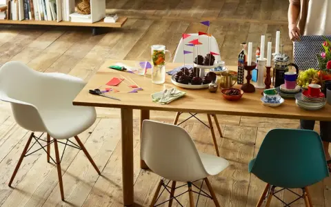 Tavolo in legno con sedie Eames House, cupcake, candele e fiori. Un'atmosfera accogliente per una festa.