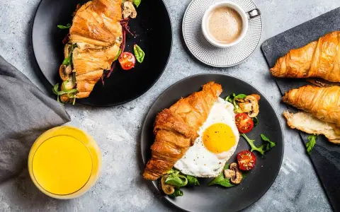 Typowe amerykańskie śniadanie: croissant z jajkiem sadzonym, pomidorkami i grzybami, do tego kawa i sok.
