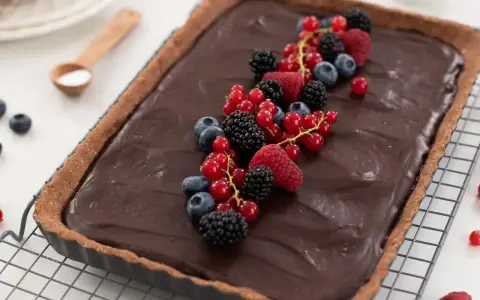 Tarta de chocolate cremosa decorada con frutos rojos frescos: frambuesas, moras, arándanos y grosellas.