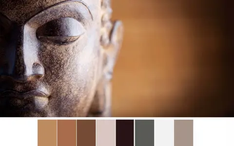 Gros plan sur le visage d'une statue de Bouddha aux tons terreux, avec une palette de couleurs apaisantes.
