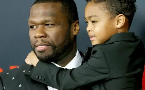 50 Cent z synem, chłopiec w czarnym garniturze przytula się do ojca.