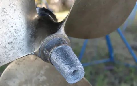 Gros plan sur l'hélice d'un bateau, montrant l'usure de l'anode et les détails gravés.