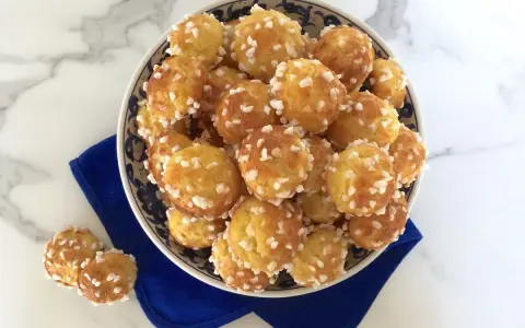 Chouquettes dorées saupoudrées de sucre perlé, prêtes à être dégustées. Une recette chouquette meilleur pâtissier pour un goûter gourmand.