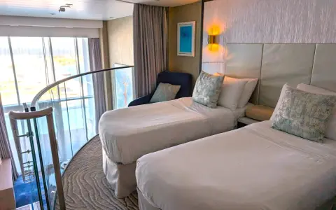 Ecco cosa trovo in cabina MSC: due letti singoli, una poltrona blu, quadri astratti e una grande finestra con vista panoramica.