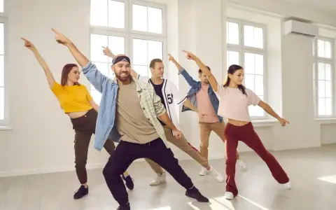 Grupa ludzi ćwiczy energiczne samba kroki w jasnej sali tanecznej, z rękami uniesionymi w rytm muzyki.