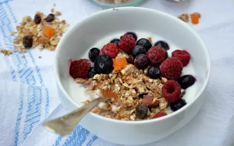 En skål med yoghurt, fil och flingor toppad med färska hallon, blåbär och torkad frukt. En perfekt start på dagen!
