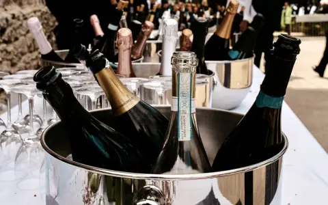 Mehrere Flaschen Sekt in einem silbernen Eiskübel, bereit für die Feier. Gläser stehen daneben.