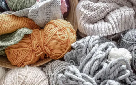 Ovillos de lana y tejidos de punto en tonos tierra y grises. El suave **merino material** invita a crear prendas cálidas y acogedoras.