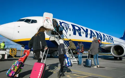 Ludzie z bagażami wsiadają do samolotu Ryanair. Może to być początek podróży lub sytuacja, gdy ktoś planuje **Ryanair zwrot biletu**.