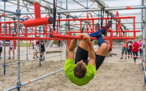 Mann hangelt sich kopfüber durch einen Hindernisparcours. Ein echter **obstacle run**!