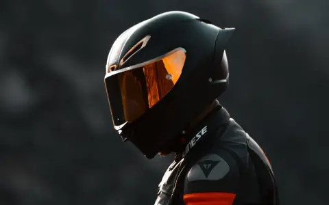 Casco nero lucido con visiera arancione riflettente, pronto per un giro in moto.