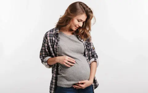 Kobieta w ciąży delikatnie dotyka brzucha. Częste oddawanie moczu w ciąży to normalny objaw.