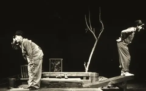 Dwóch mężczyzn w kapeluszach na scenie, w surrealistycznej scenografii. Scena z eugène ionesco sztuki, pełna absurdu i niepokoju.