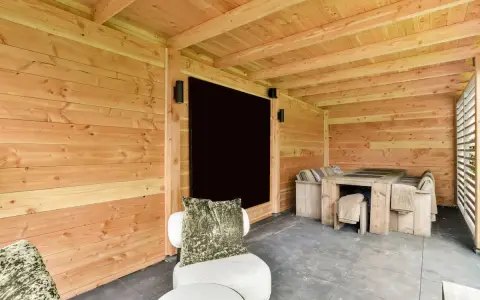Un'accogliente dependance in legno con tavolo e sedute, perfetta per idee di relax all'aperto.