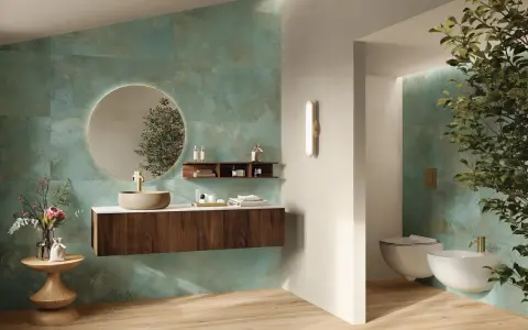 Elegante bagno verde petrolio e legno con lavabo in pietra, specchio rotondo e bidet sospeso.