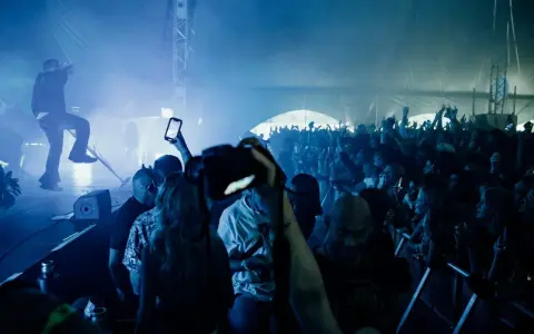 Publik jublar på en konsert i Göteborg. En artist uppträder på scenen i blått ljus och rök. Många i publiken filmar med sina mobiler.