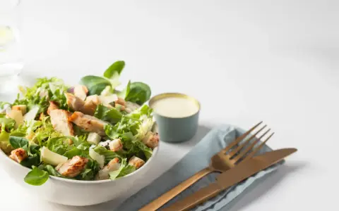 Salade César fraîche avec poulet grillé, croûtons et copeaux de parmesan, accompagnée de sa sauce crémeuse.