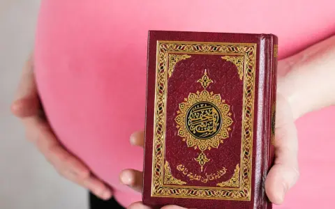 Schwanger, hält eine Frau den Koran. Im Islam gibt es Erleichterungen beim Fasten während der Schwangerschaft.