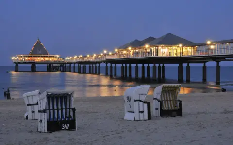 Strandkörbe am Abend vor der beleuchteten Seebrücke in Heringsdorf. Ein perfekter Ort für Geheimtipps am Meer.