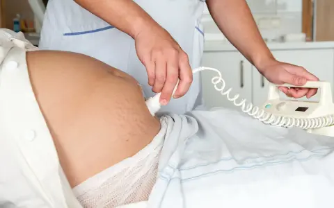 En barnmorska utför en ultraljudsundersökning på en gravid mage, en del av specialistmödravård.