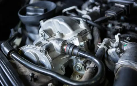 Primer plano del motor de un coche, mostrando el alternador y otras piezas. Podría ser la causa de un fallo alternador coche.