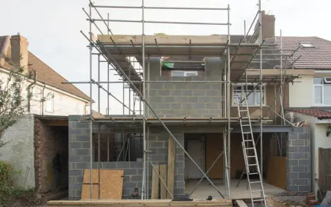 Construction d'une maison : échafaudages, blocs de béton, poutres métalliques. Penser à tout quand on fait construire sa maison.