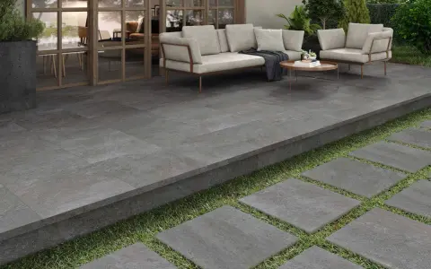 Terraza moderna con suelo de baldosas grises, ideal para saber como poner baldosas en suelo de tierra. Sofá y sillones invitan al descanso.