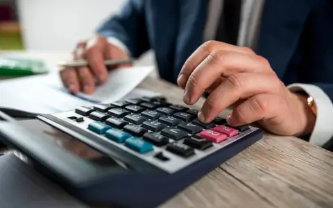 Man con traje calculando en calculadora. Los suplidos llevan IVA, un detalle importante en la contabilidad.