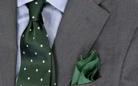 Zielony krawat w kropki do niebieskiej koszuli i szarej marynarki. Elegancka stylizacja.