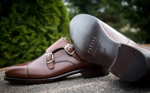 Eleganckie brązowe buty z podwójnymi klamrami, wykonane z wysokiej jakości kruponu. Widoczna podeszwa z logo marki.