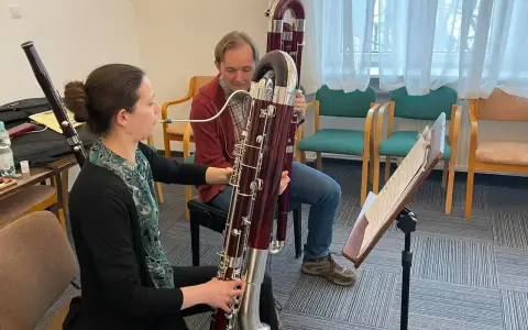 Kobieta i mężczyzna ćwiczą grę na fagotach. Jaki to instrument? Dwa duże, drewniane instrumenty dęte drewniane, fagot, są w centrum uwagi.